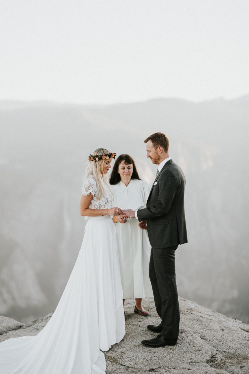This photo is of a bride and groom exchanging their rings during their elopement at Taft Point