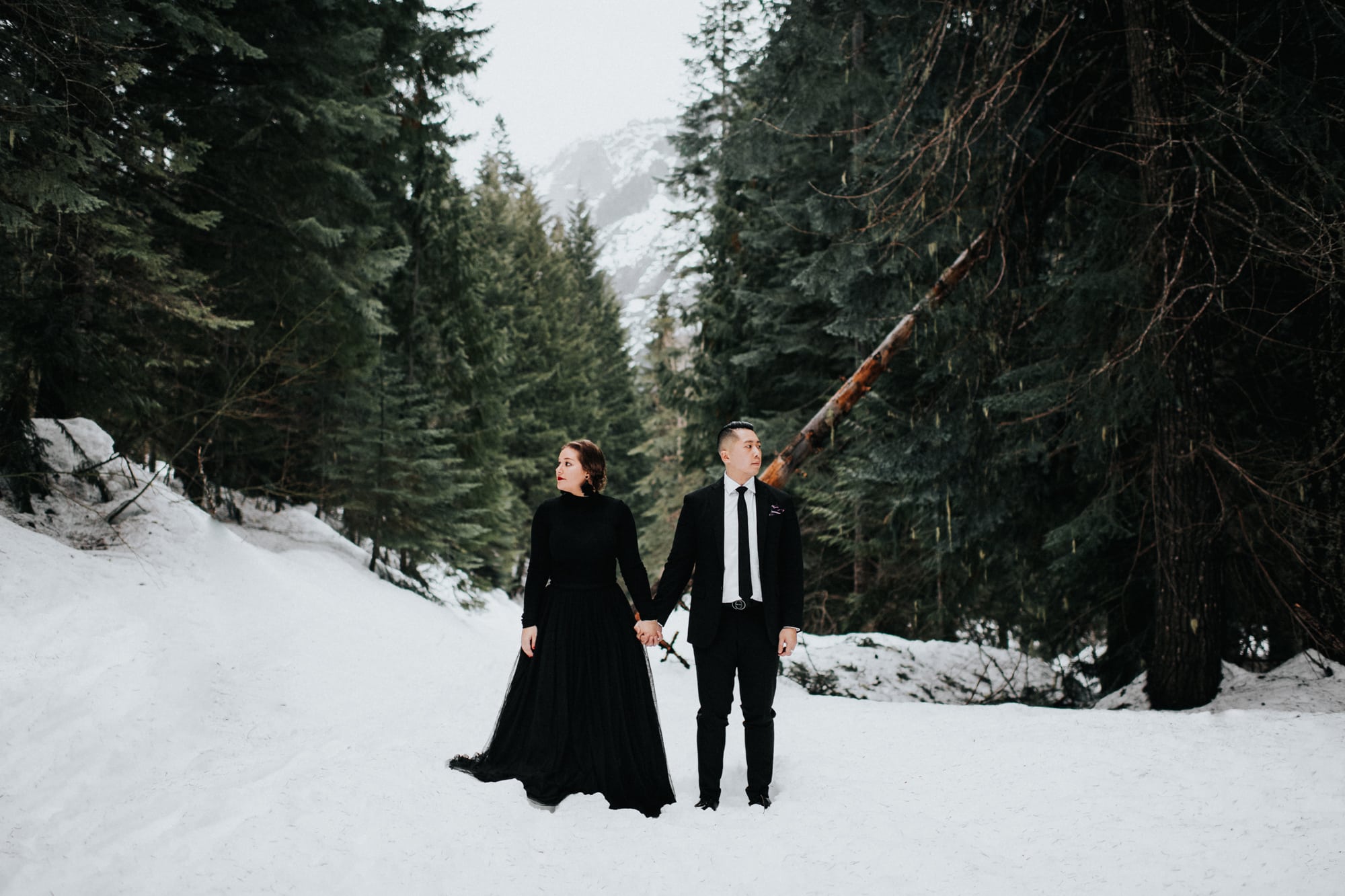 couple hiking in the snow for their engagement photos at tall timber ranch