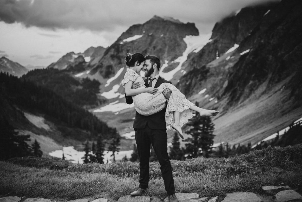 black and white of groom holding bride in fireman carry