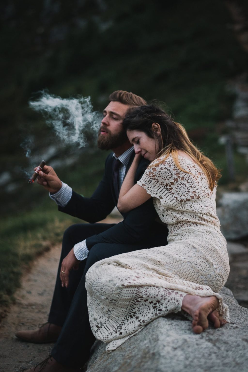 groom smoking his cigar while bride rests her head on his shoulder