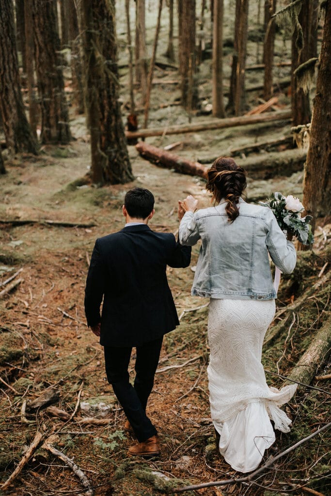 bride and groom holding hands hiking in the woods