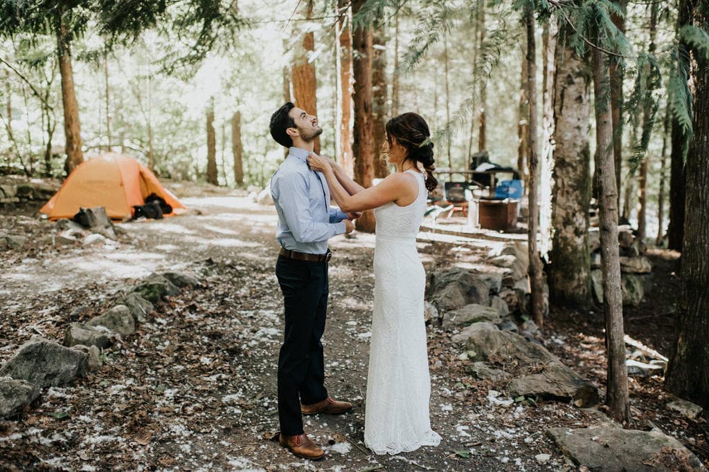 bride helping groom get ready at their campsite