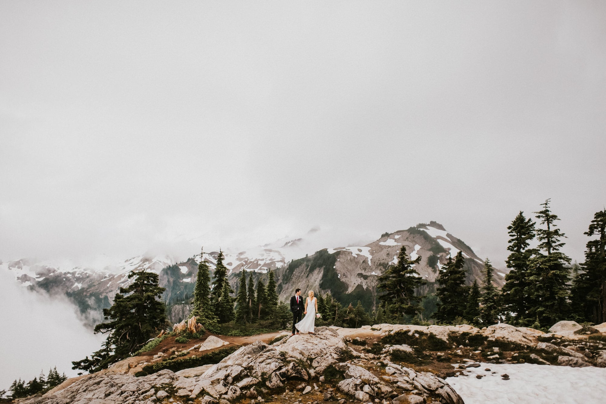 bride and groom holding hands on top of a mountain
