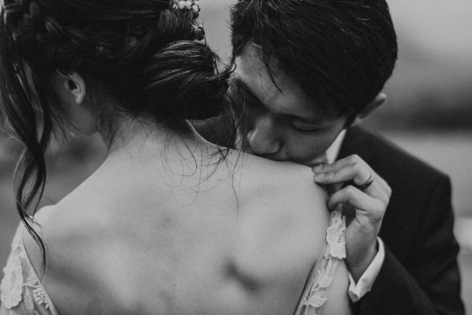groom kissing brides shoulder in black and white