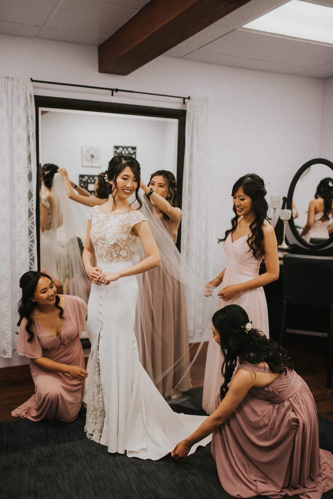 bride getting her dress on with bridesmaids