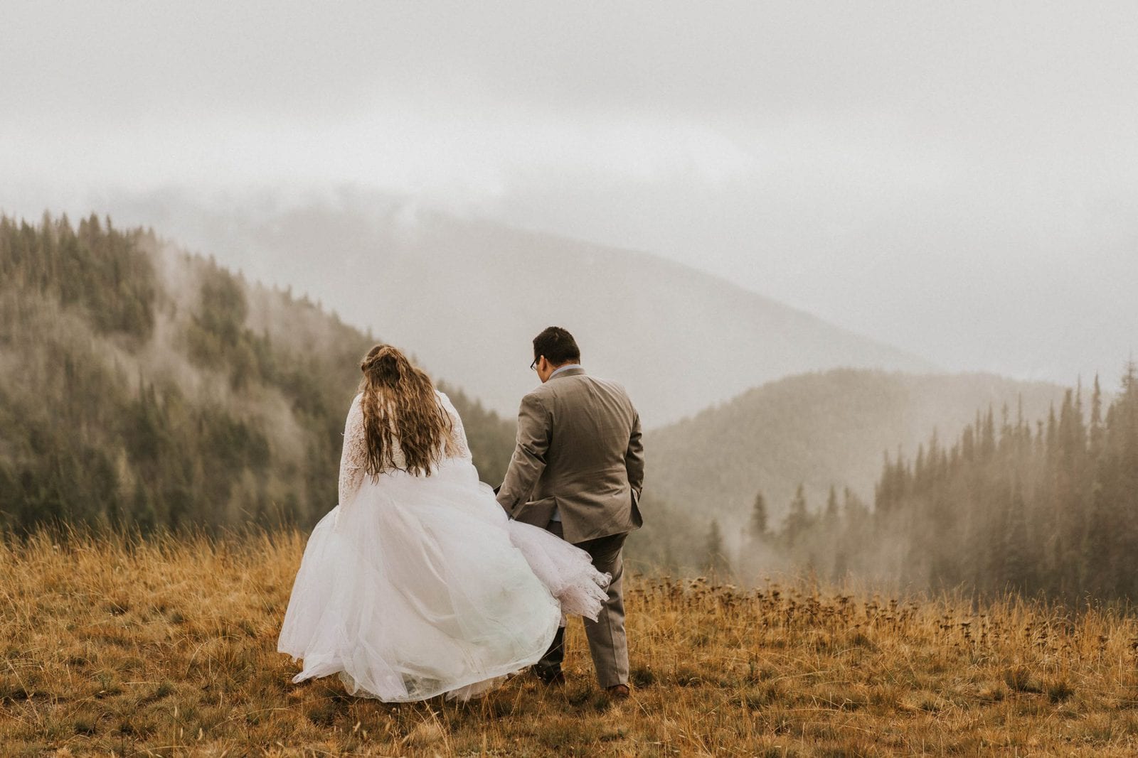 bride and groom walking toward mountain views
