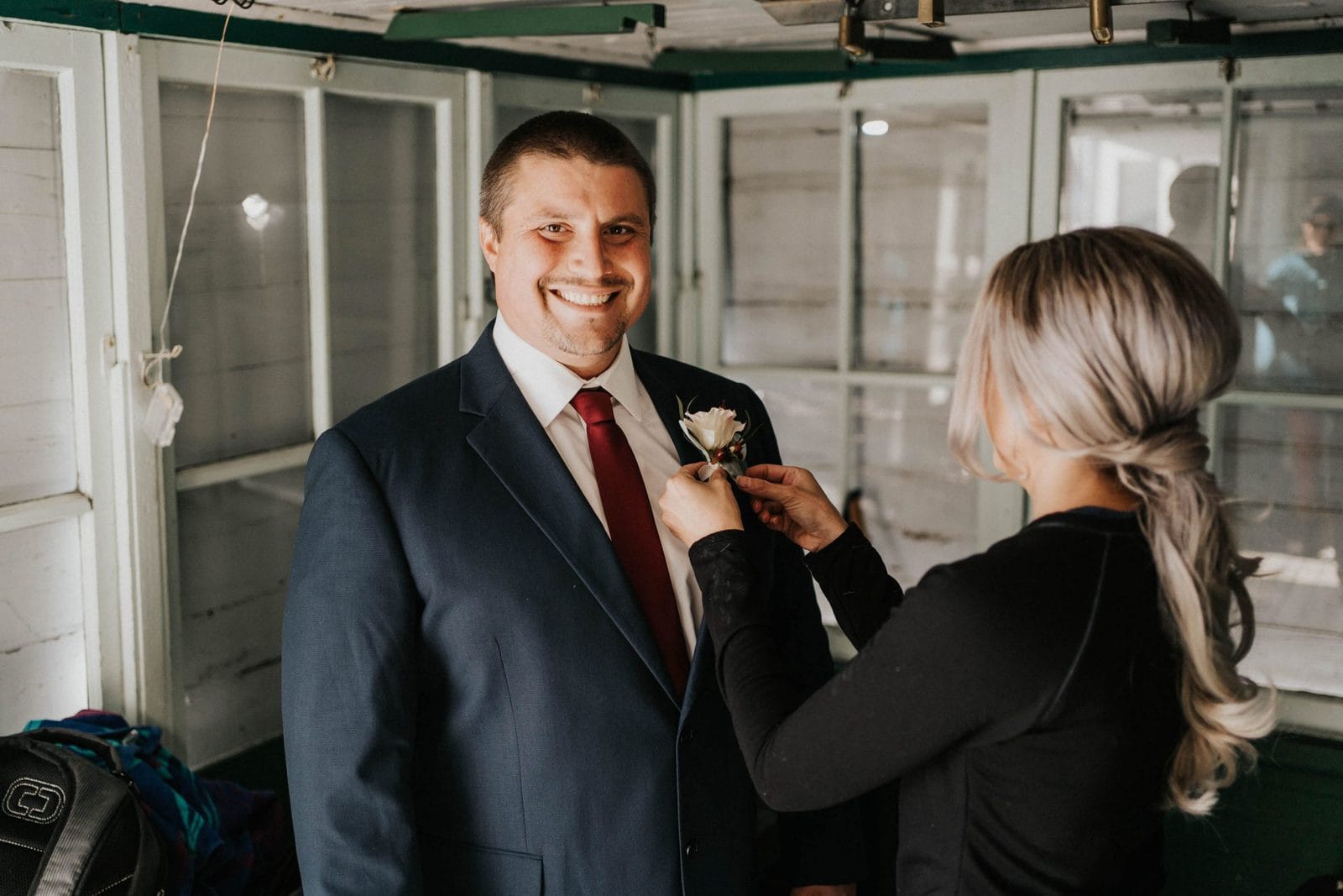 bride helping groom with his boutonnière